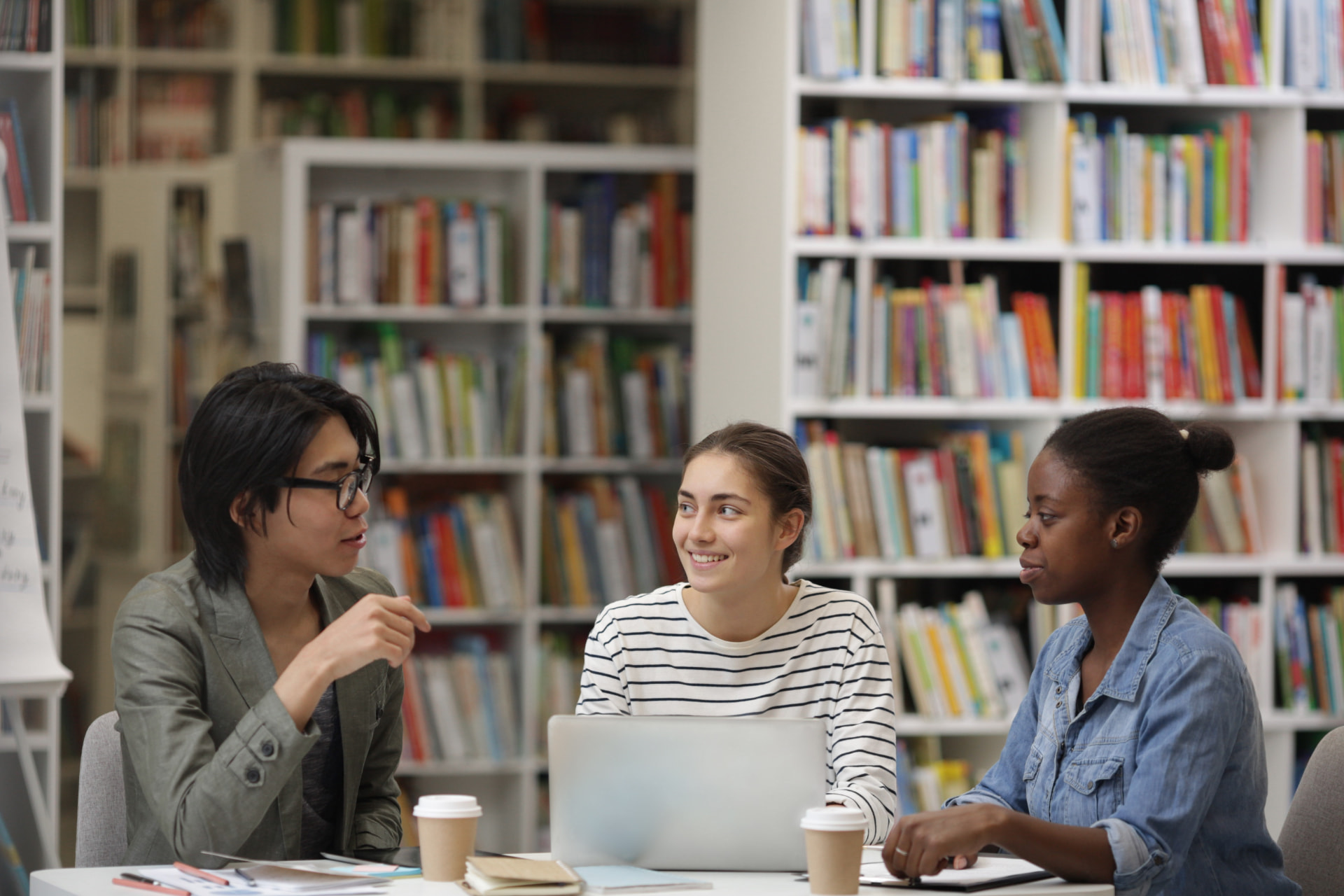 Three students discussing together in a library