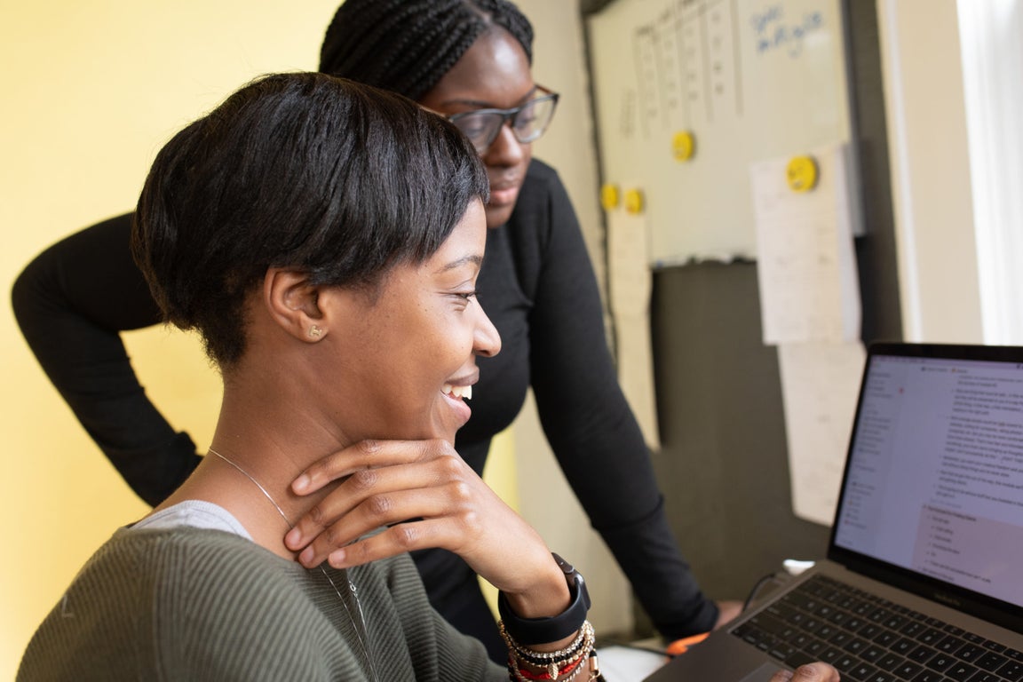 Two educators collaborating at a laptop in a classroom
