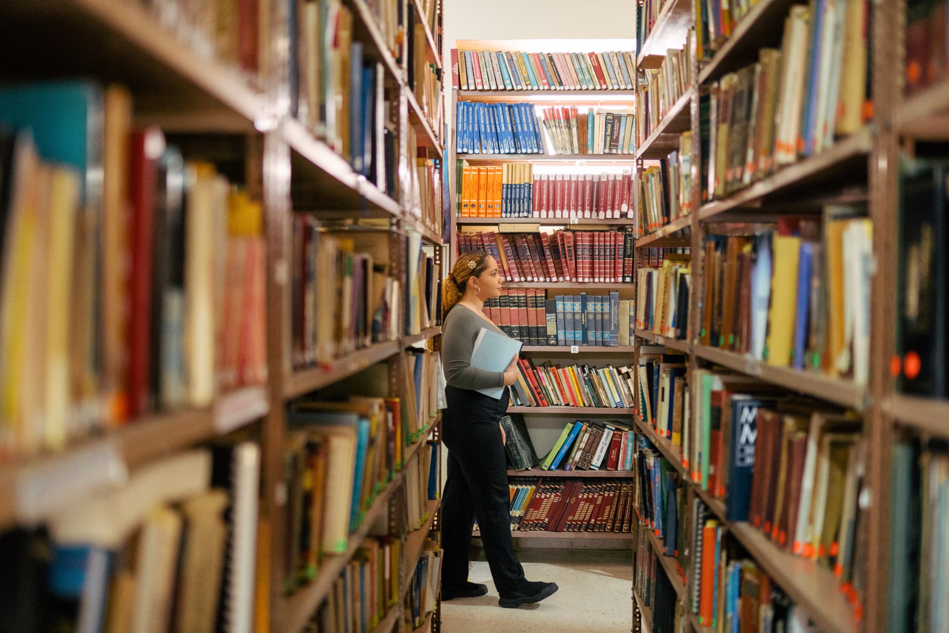 A person browsing books in a tall library aisle